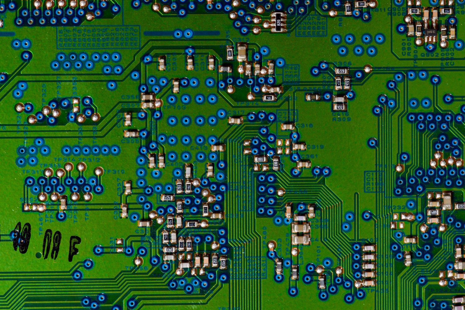 Close-up of a green printed circuit board covered in soldered chips and components.