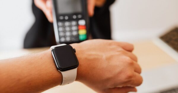 Person making a contactless payment using a smartwatch at a cashless checkout counter.