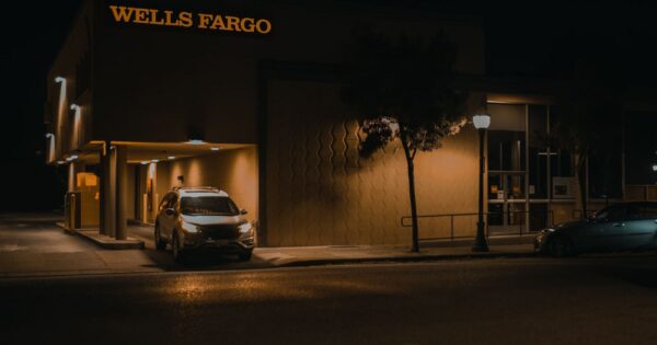 Illuminated Wells Fargo bank branch at night showcasing modern architecture and signage.