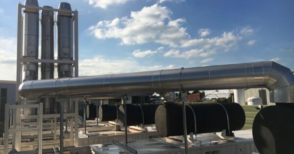 Modern industrial chimneys and support mast with flues against a clear blue sky, showcasing advanced infrastructure.