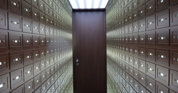 Wooden lockboxes line the walls of a modern, secure vault with a central wooden door.