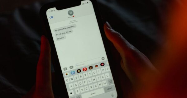 Close-up of a breakup message on a smartphone screen, held in hands, evoking emotions.