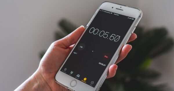 Close-up of a hand holding a smartphone with a stopwatch app running.