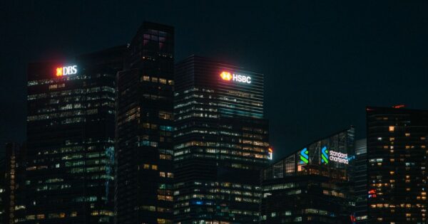Illuminated city skyscrapers of major banks in Singapore's financial district at night.