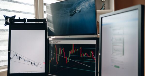 A home office setup featuring multiple monitors displaying trading charts and data analysis.