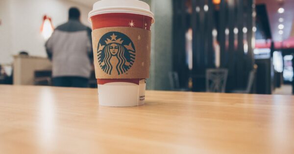 Close-up of a Starbucks coffee cup on a wooden table in a cozy café setting.