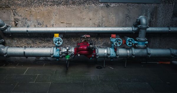 A detailed view of industrial pipes with colorful valves on a textured wall.