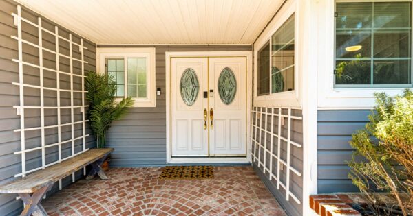Welcoming residential porch with double doors and brick flooring.