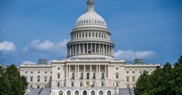 A frontal view of the iconic US Capitol Building in Washington D.C. under blue skies.
