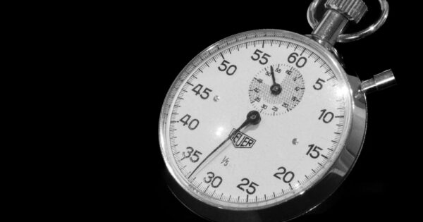 Vintage mechanical stopwatch with black dial against a dark background