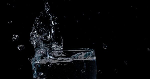 Close-up of water splashing in a glass against a black background.