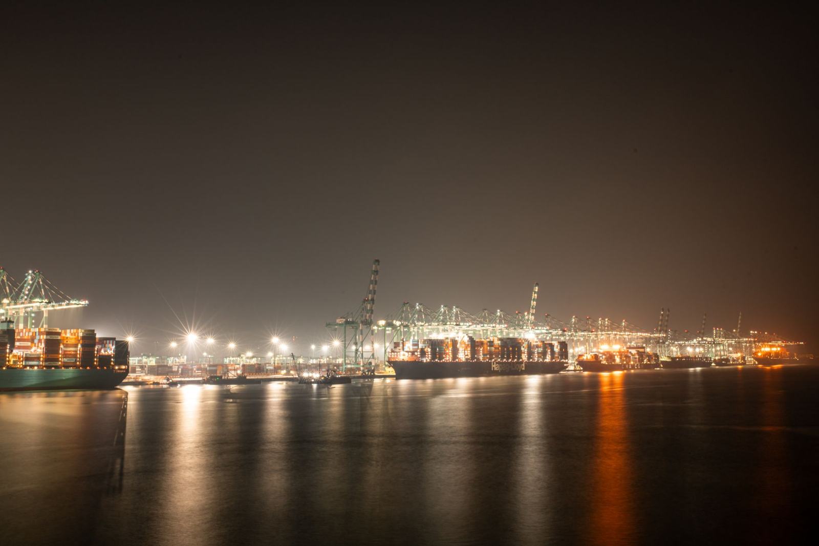 Luminous night view of a bustling industrial port with cargo ships.