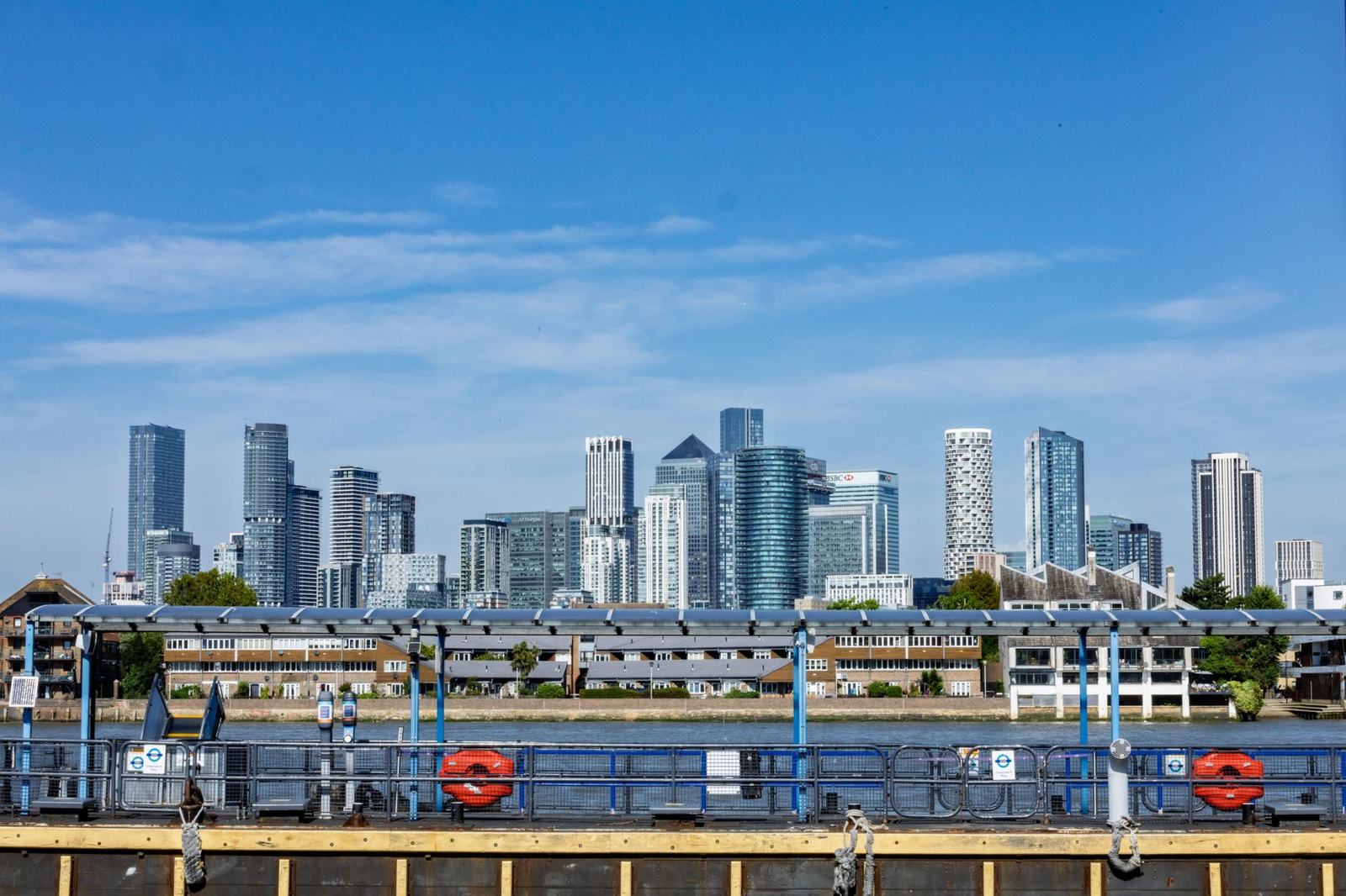 View of the iconic Canary Wharf skyline in London with blue skies and modern architecture.
