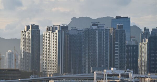 Cityscape featuring towering high-rise buildings against a mountainous backdrop.