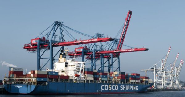 COSCO shipping vessel docked at Hamburg port terminal for global freight transport.