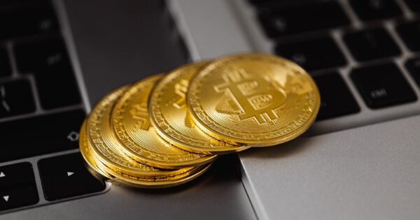 Close-up of golden bitcoins on a laptop keyboard representing digital currency and wealth.