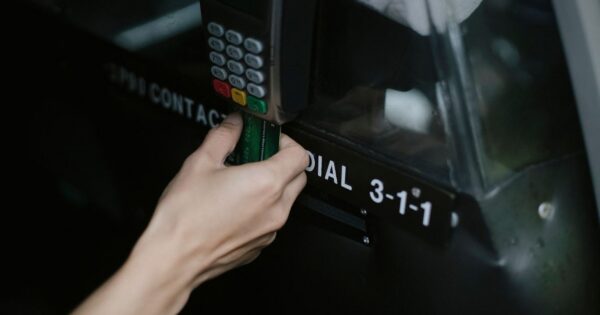 Crop anonymous traveler using card device while paying for taxi ride in automobile